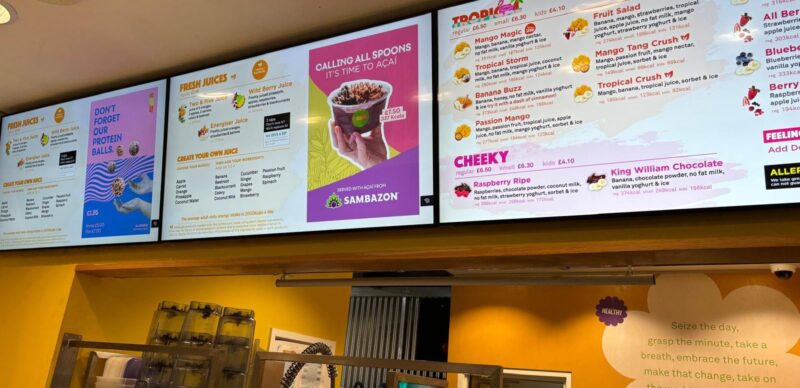 Row of digital menu board screens above a food service counter
