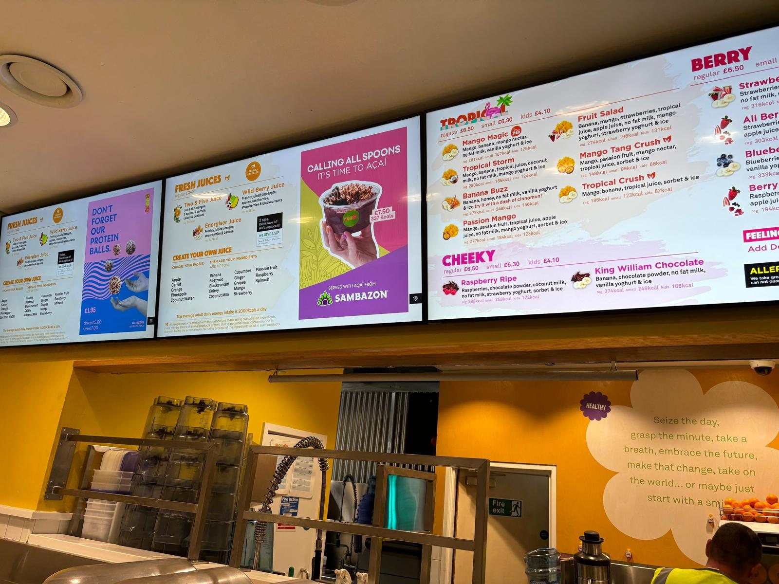 Row of digital menu board screens above a food service counter