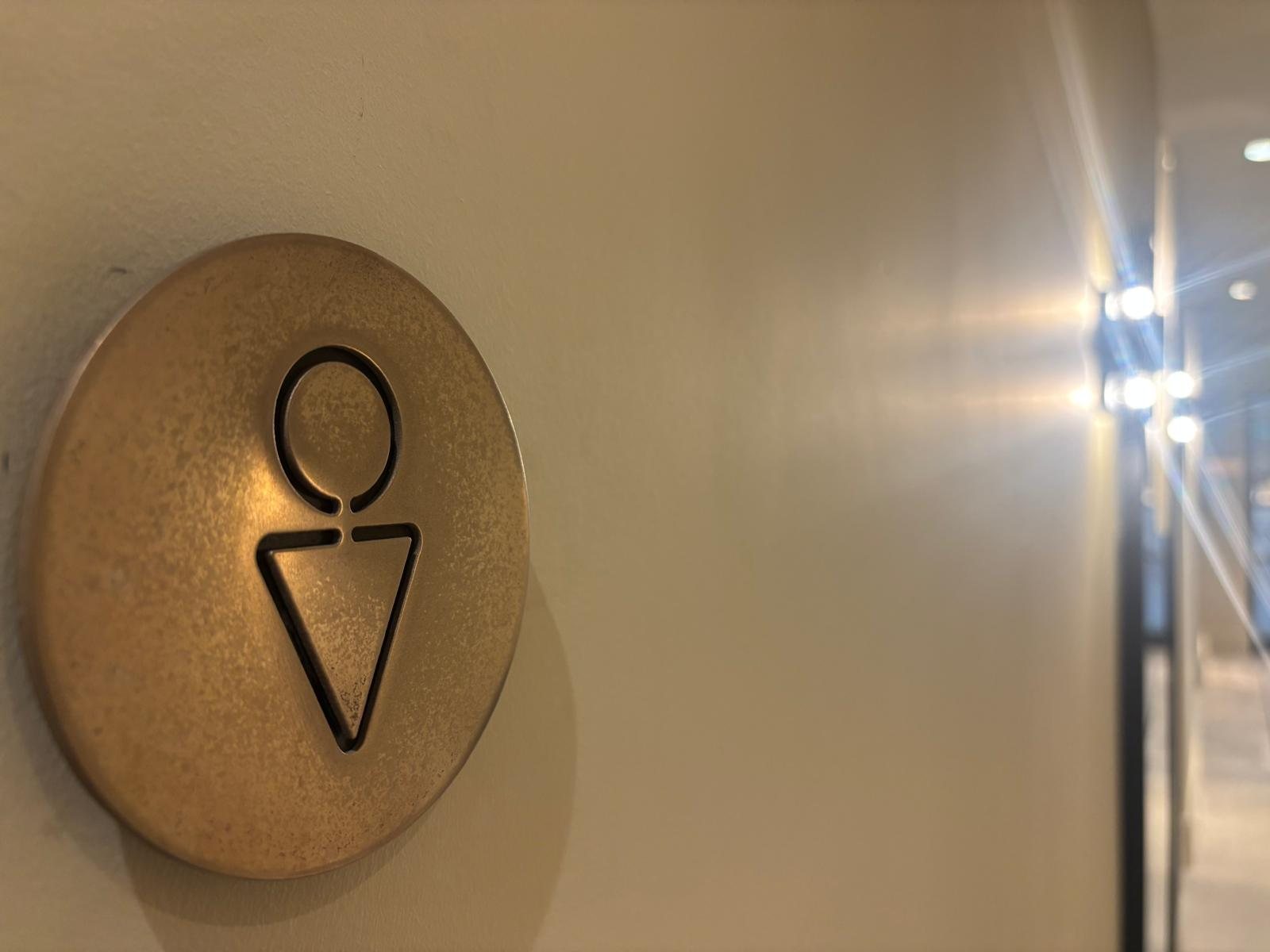 Bronze finish tactile toilet sign with raised pictogram