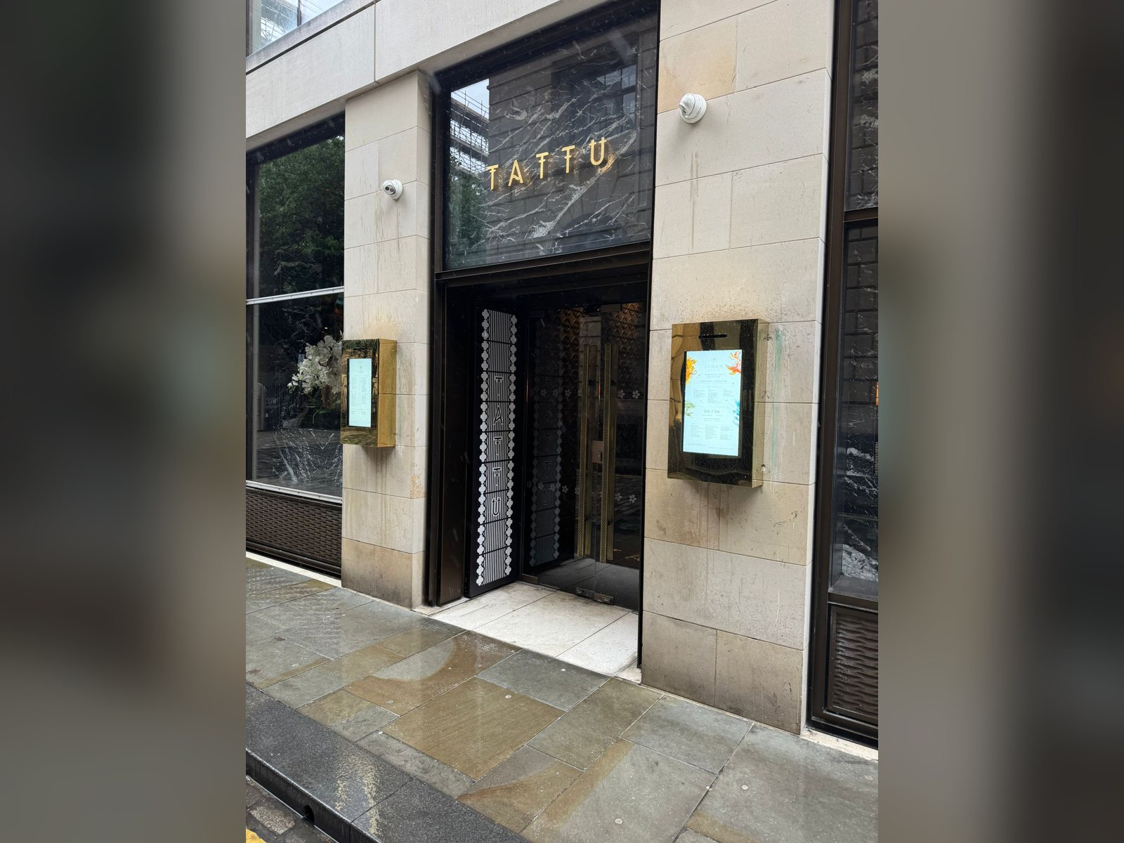 Pair of digital menu screens in bronze housings either side of a restaurant entrance
