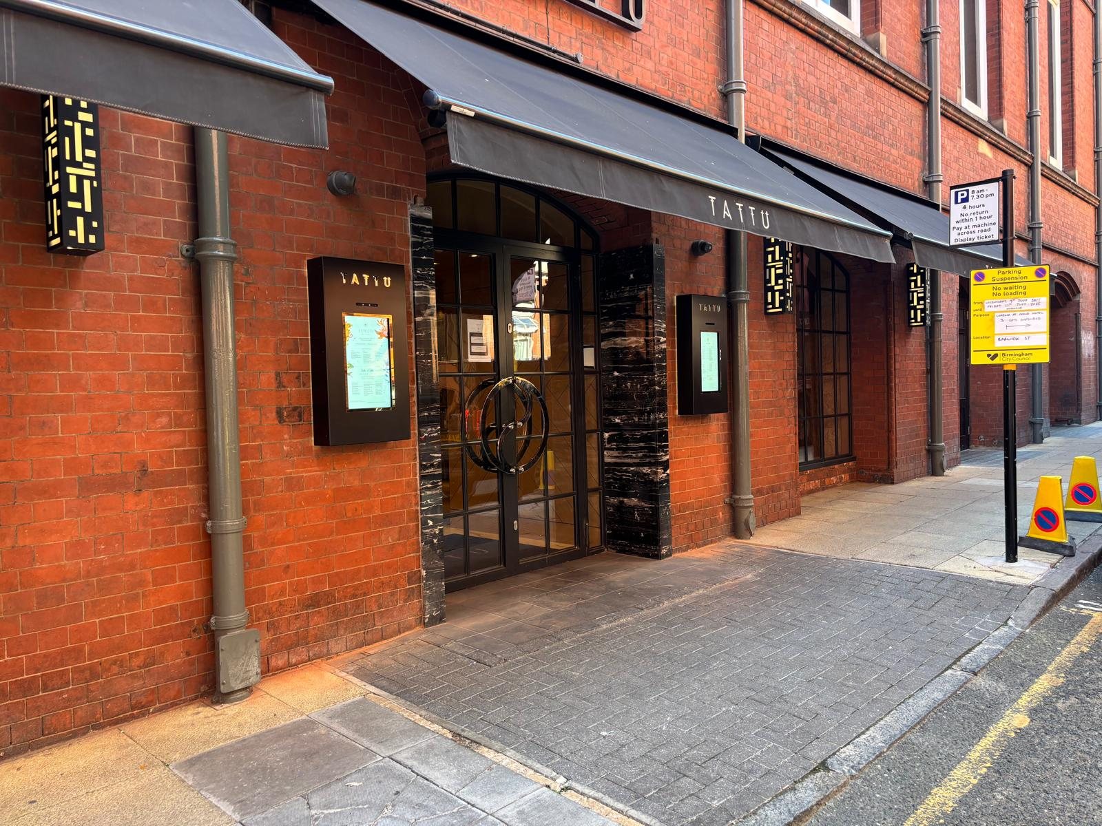 Outdoor digital menu screens in branded housings along a Manchester restaurant frontage