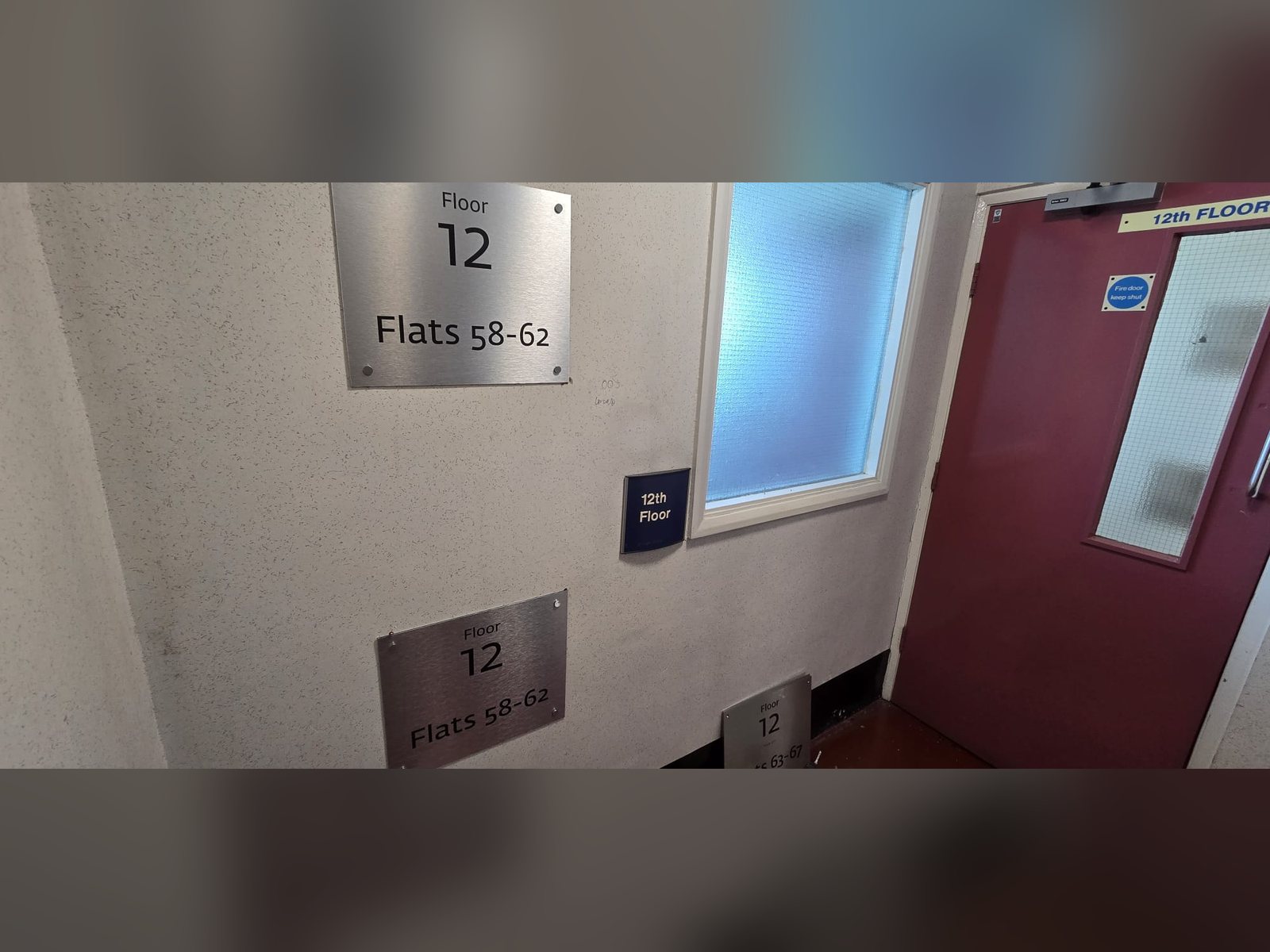 Brushed stainless steel tactile floor level sign in a residential stair core
