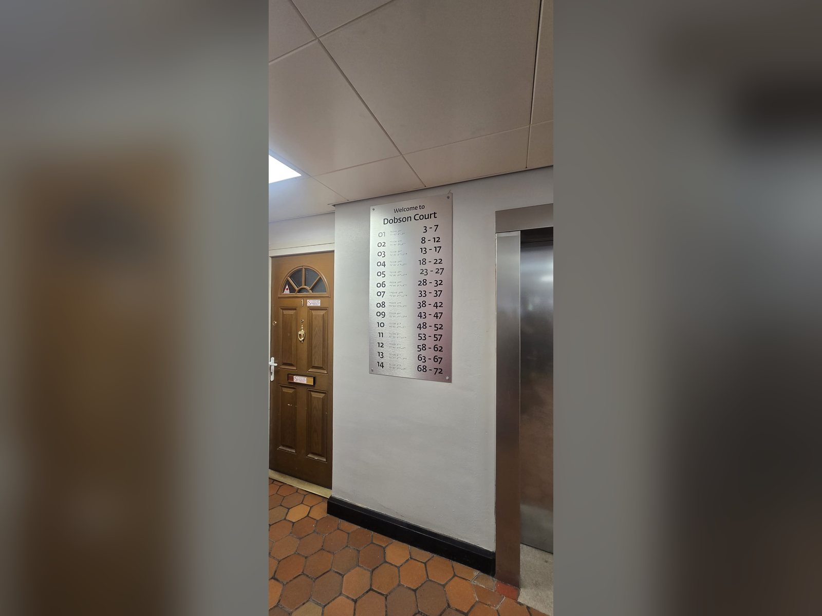 Tactile floor directory sign beside a lift in a residential building