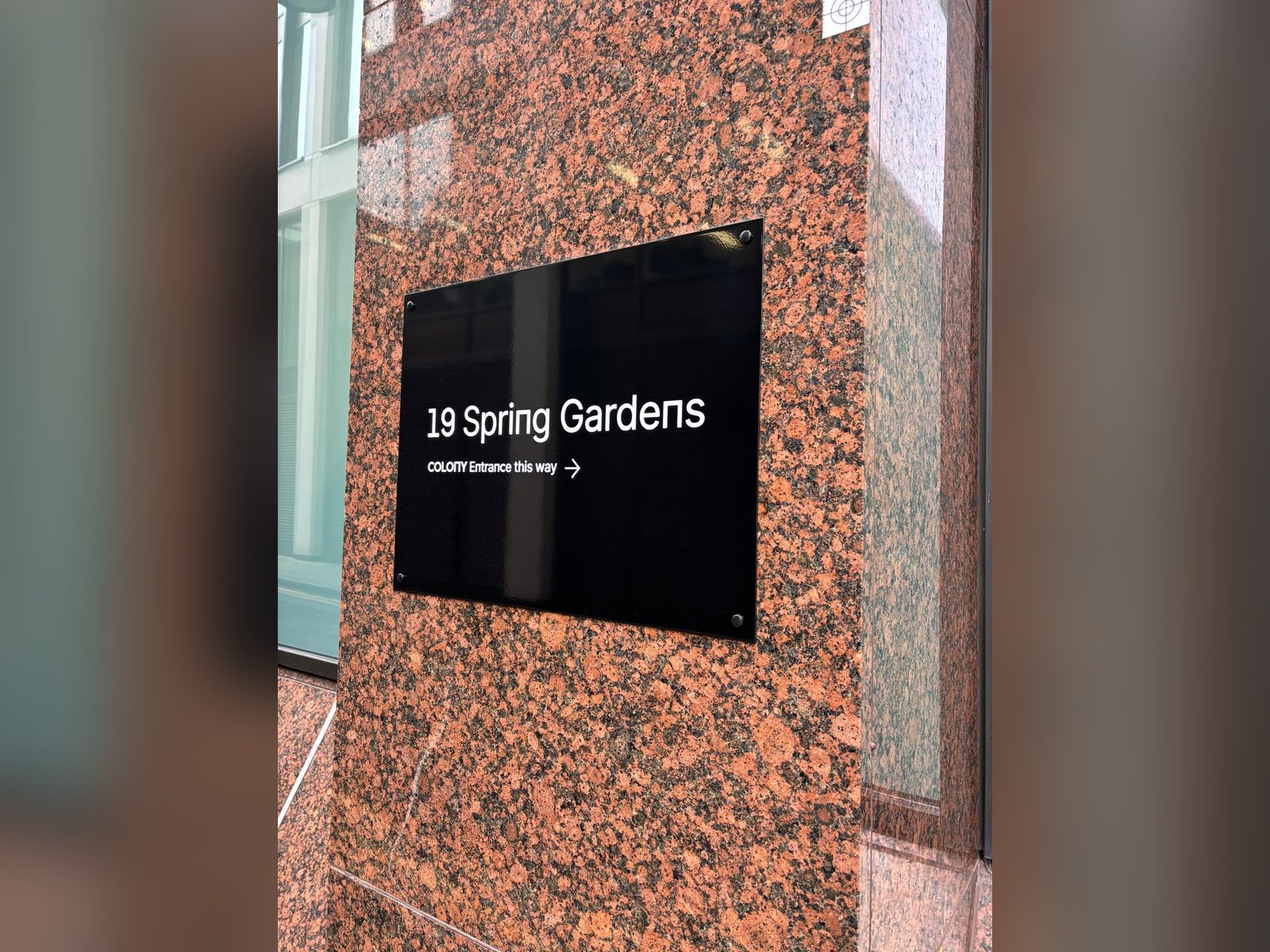 Building entrance sign with raised lettering on a granite facade in Manchester