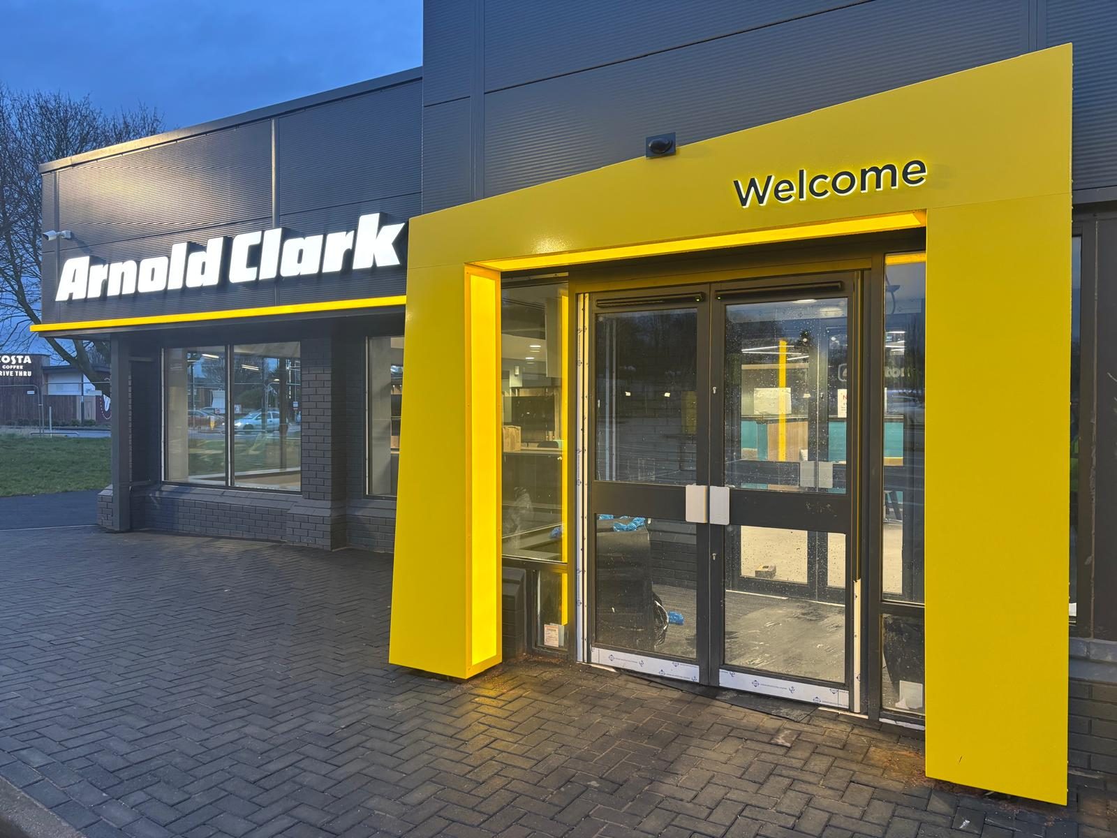 Illuminated yellow entrance portal at a car dealership