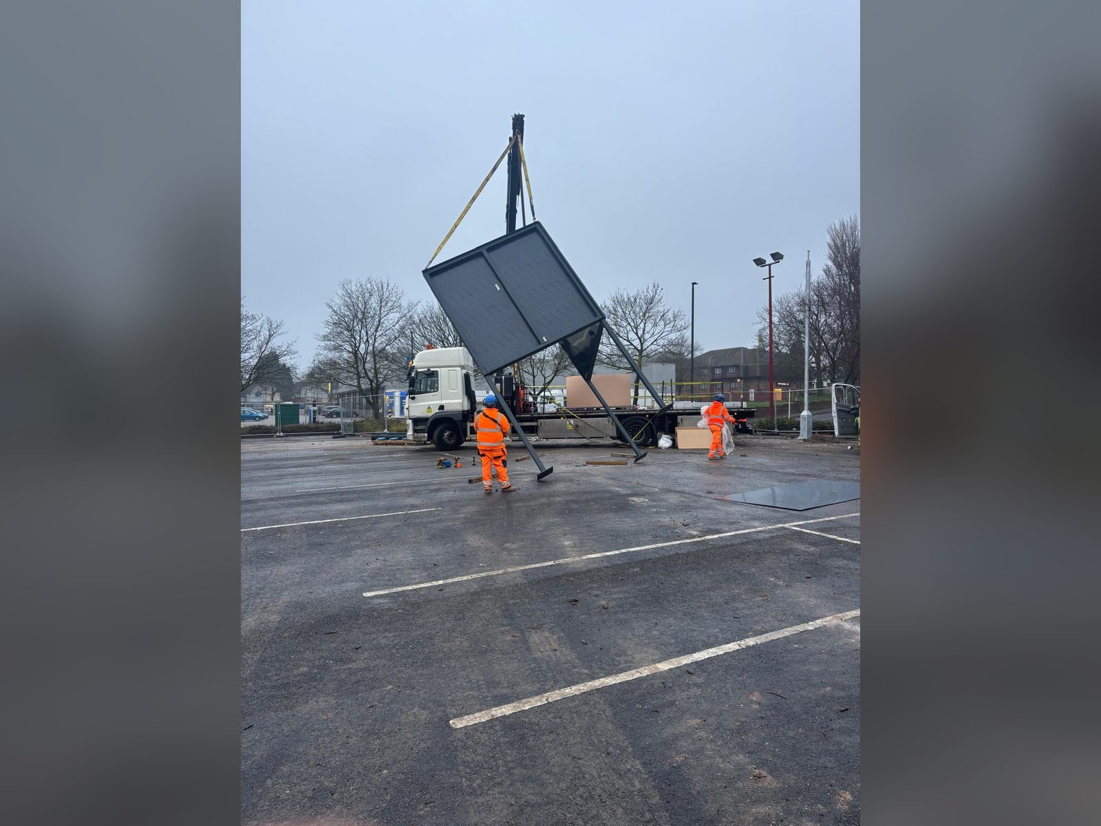 Large sign structure being lifted into place by crane