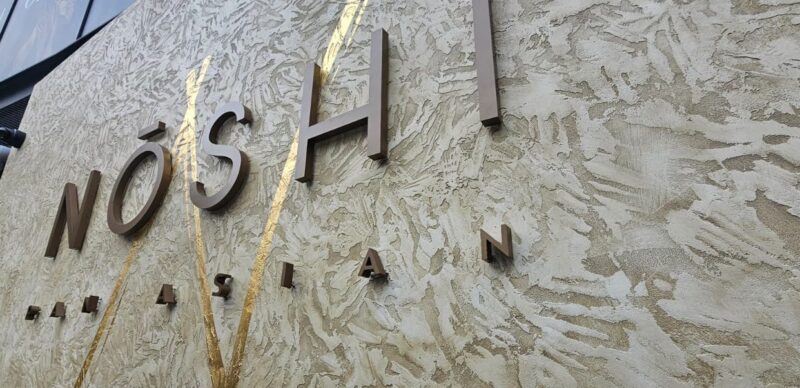 Brushed metal letters and gold leaf detail on a restaurant wall