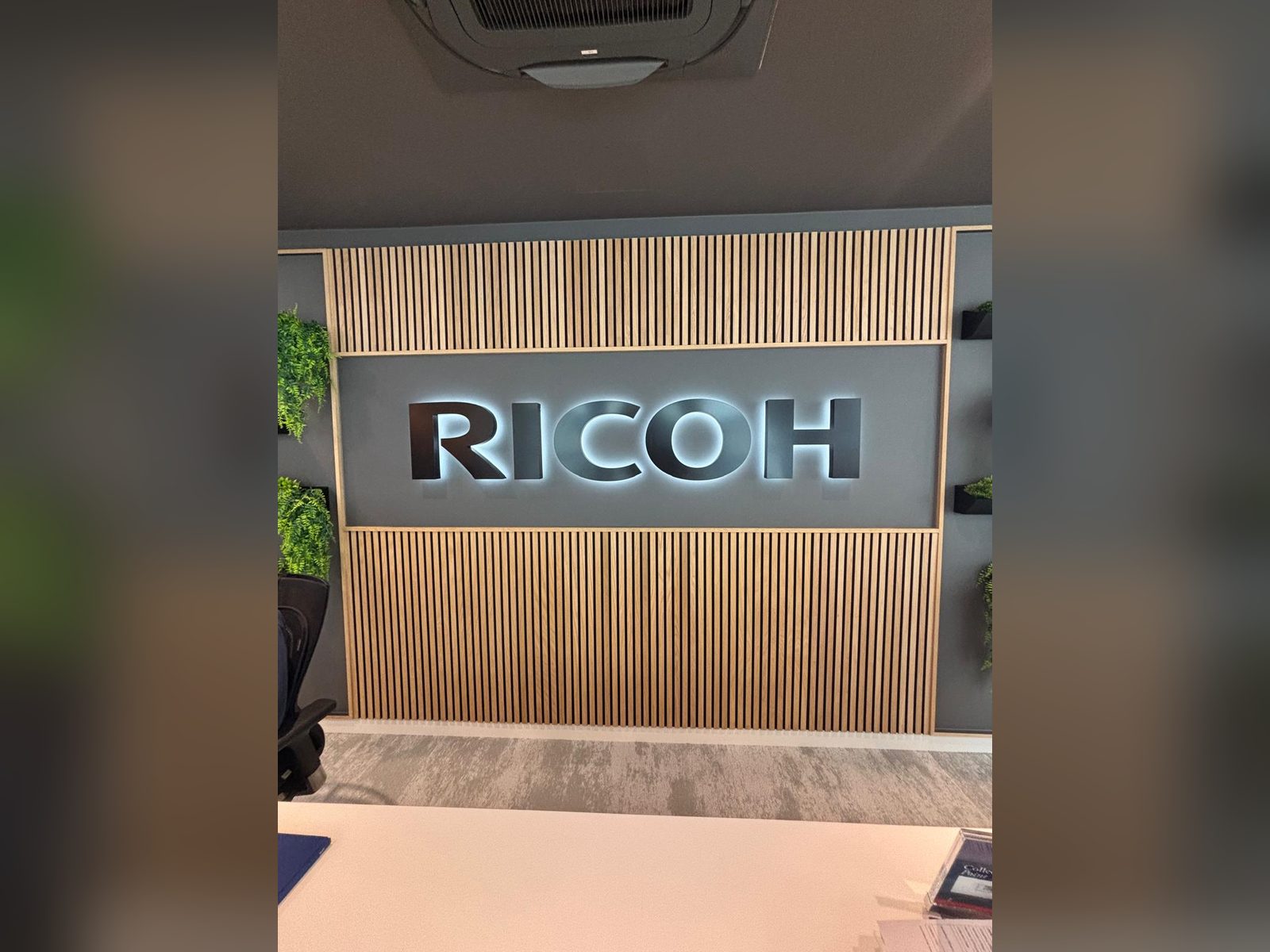 Halo lit built up letters on a timber slatted reception wall