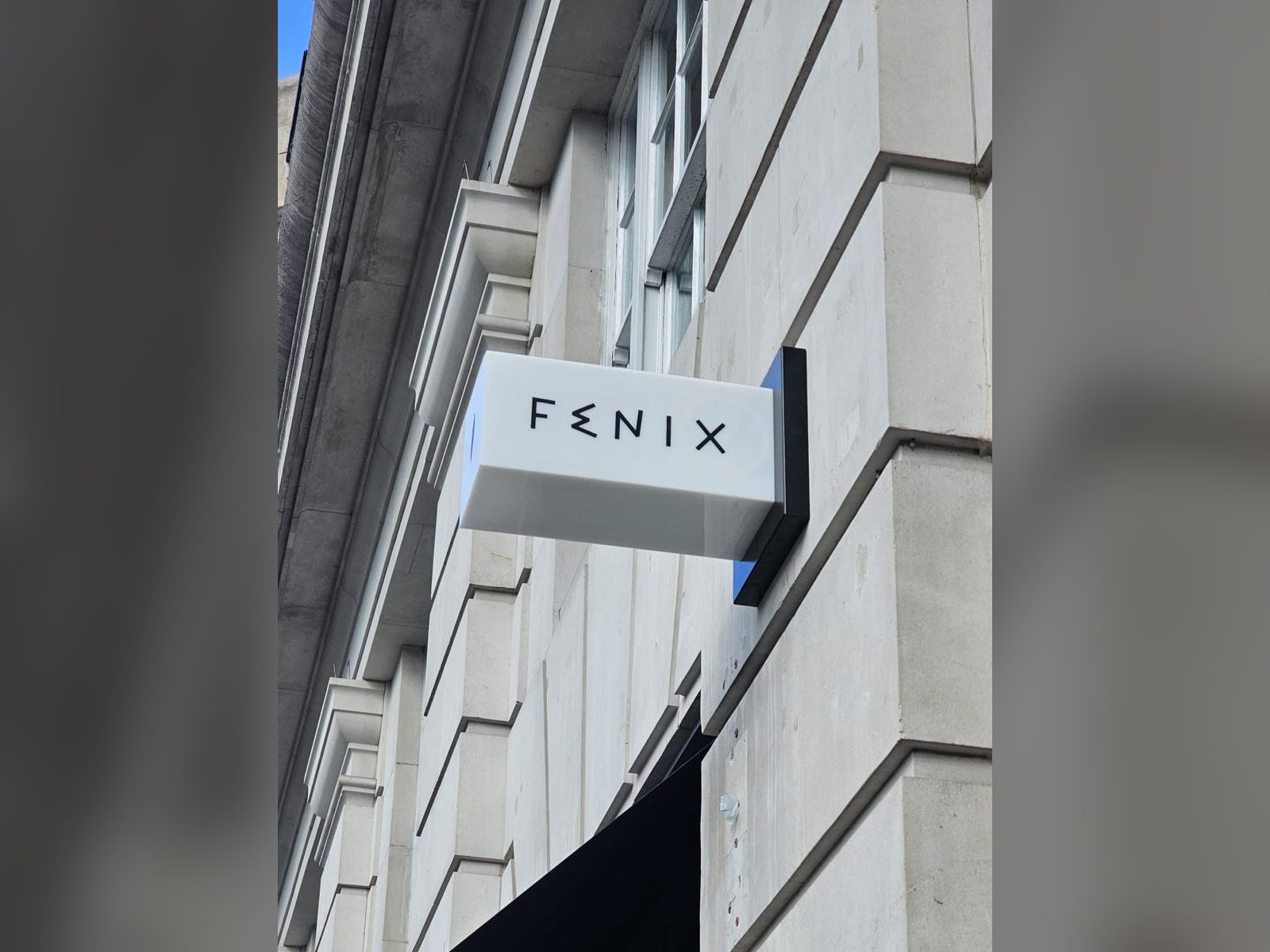 Projecting box sign on a stone building facade