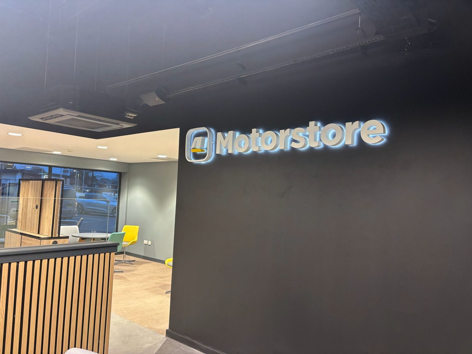Illuminated logo on a dark reception wall in a car dealership