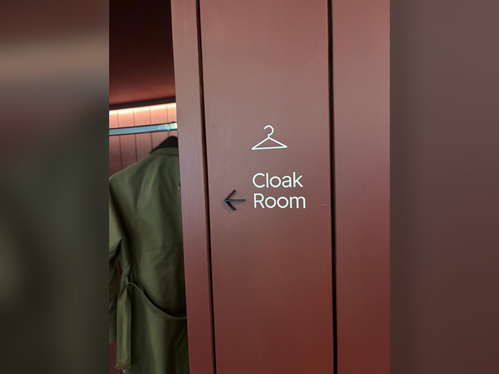Cloakroom directional sign on a timber panelled wall