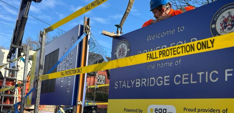 Totem sign being installed by crane with fall protection in place