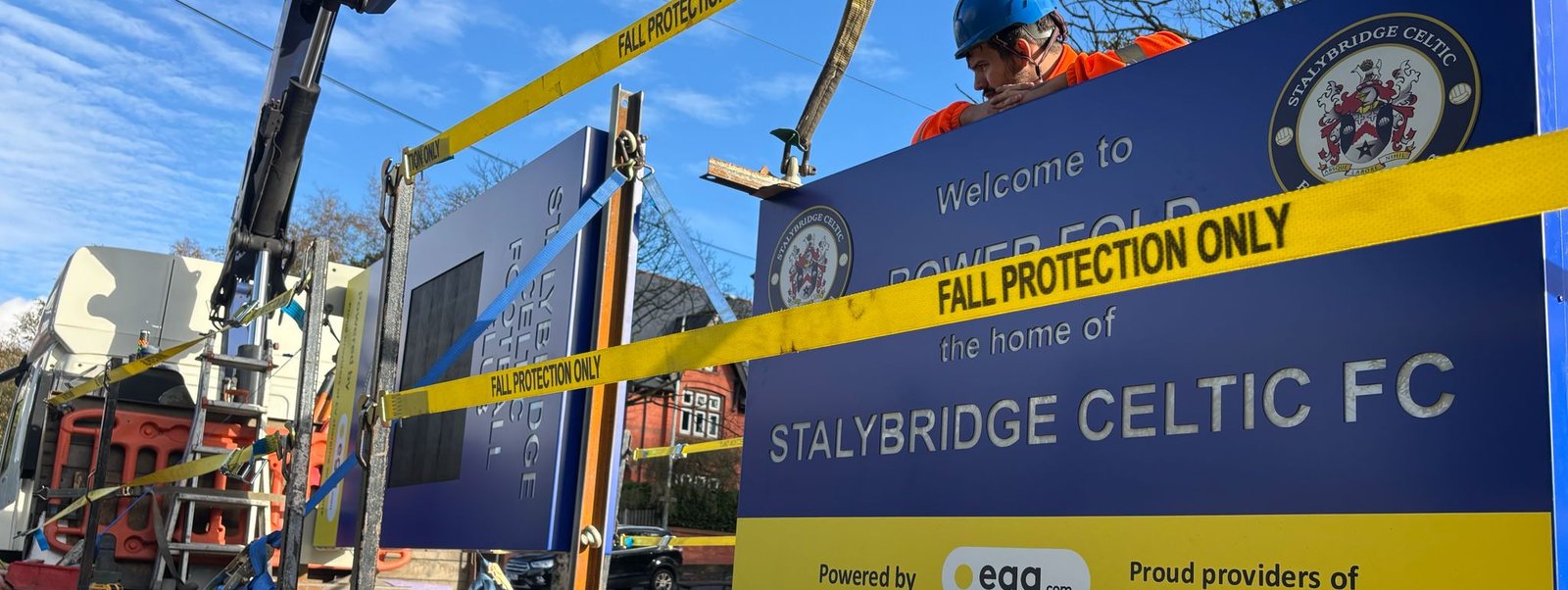 Totem sign being installed by crane with fall protection in place